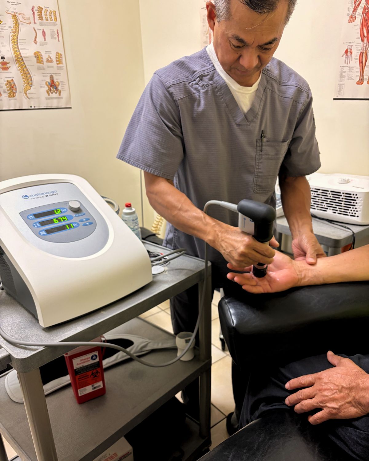 Dr. Bui applying shockwave therapy to a patient's forearm with the Chattanooga Intelect Mobile 2 RPW
